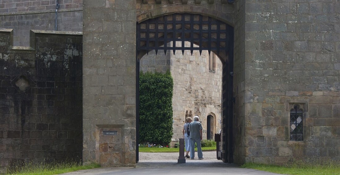 A raised iron portcullis in a stone castle gateway