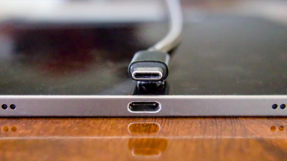 A USB-C cable plug next to a USB-C port on the edge of a laptop