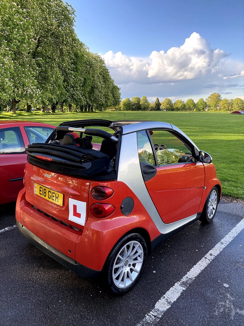A small red learner car with an L plate
